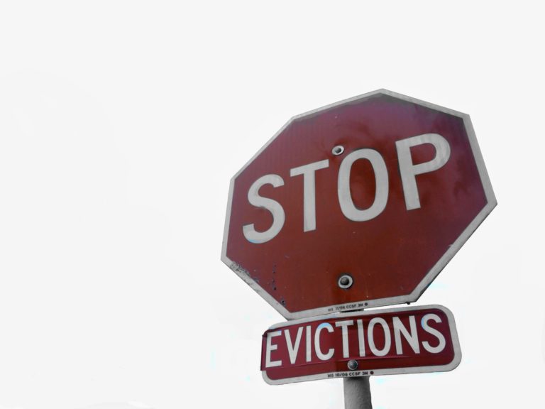 A stop sign with an added sign below it that reads "Colorado eviction," against a blank background, highlighting the ongoing rental crisis.