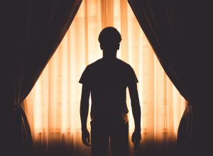 Silhouette of a person standing between curtains with a cycle of opportunity backlighting effect.