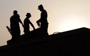 Three construction workers silhouetted against a sunset sky, embodying workforce development in action.