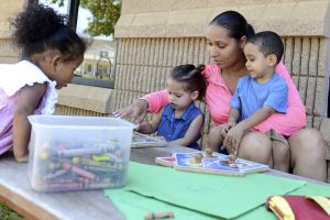A mother and her three children engaged in an outdoor arts and crafts activity as part of the Expand Pilot Program.