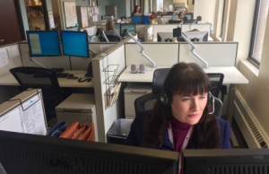 Woman working as a trusted nurse at a desk with headphones in an office environment.