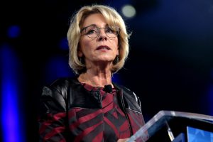 Woman giving a speech at a podium for-profit colleges.