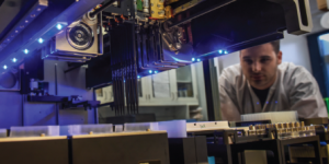 Technician undergoing training while monitoring advanced manufacturing equipment.