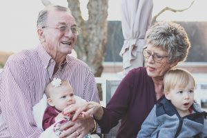 Elderly couple enjoying the economic opportunity to spend quality time outdoors with their two young grandchildren.