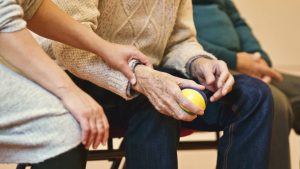 A younger person offering informal caregiving through holding an elderly person's hand, providing comfort and support.