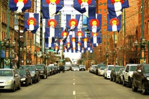 A middle-class street lined with parked cars and decorated with colorful hanging lanterns and flags.