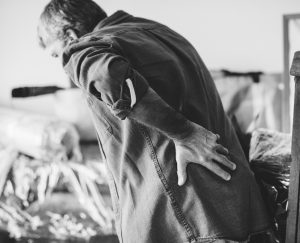 A person holding their lower back, possibly indicating discomfort or pain, may be in need of respite care.