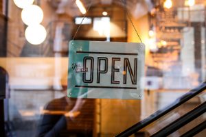 A glass "what are vendor fees" sign hanging on a shop window with reflections of interior lights.