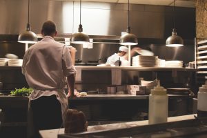 Chefs preparing meals in a busy restaurant kitchen, often considered low-wage jobs.