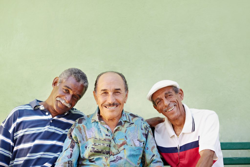 Three smiling men sitting together against a green wall in Colorado.