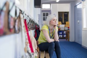 Teacher sitting contemplatively in an empty Colorado classroom.