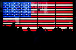 Silhouetted figures against a backlit American flag, contemplating the 2020 Policy Proposals.