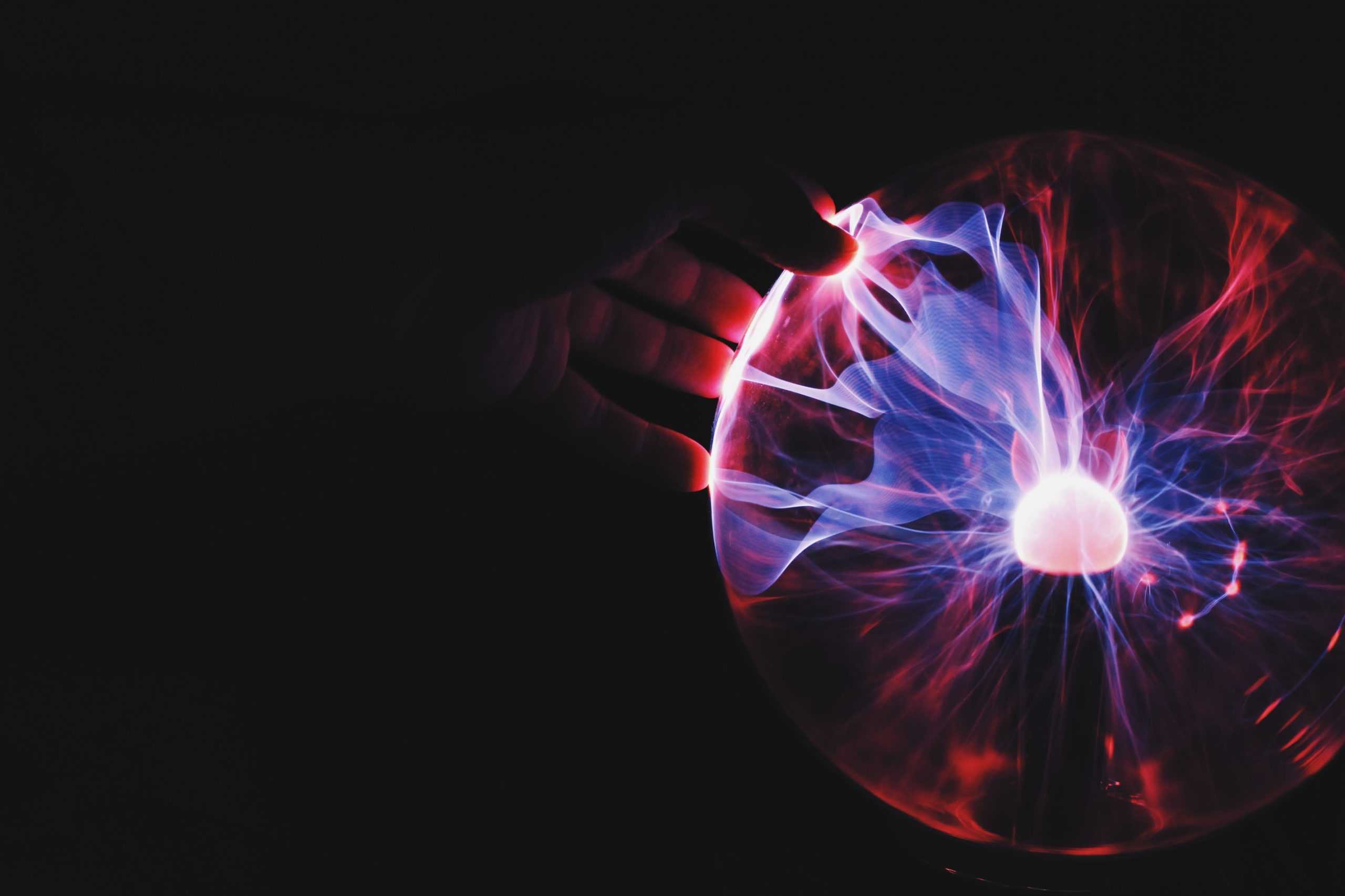 Person touching a plasma globe, with purple and pink electric streams converging on their fingertip, symbolizing the future of work.