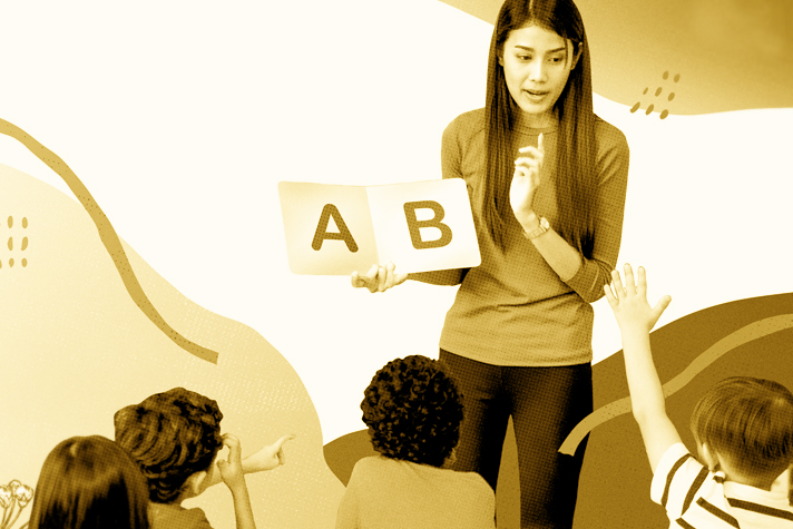 Teacher holding flashcards engages with young students in a classroom setting, incorporating the Cost of Care Model into the lesson.