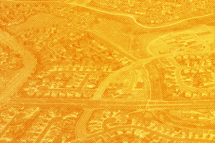 Aerial view of a suburban area with a network of streets and houses, depicted in a monochromatic orange filter, illustrating the consequences of price-cap regulations.