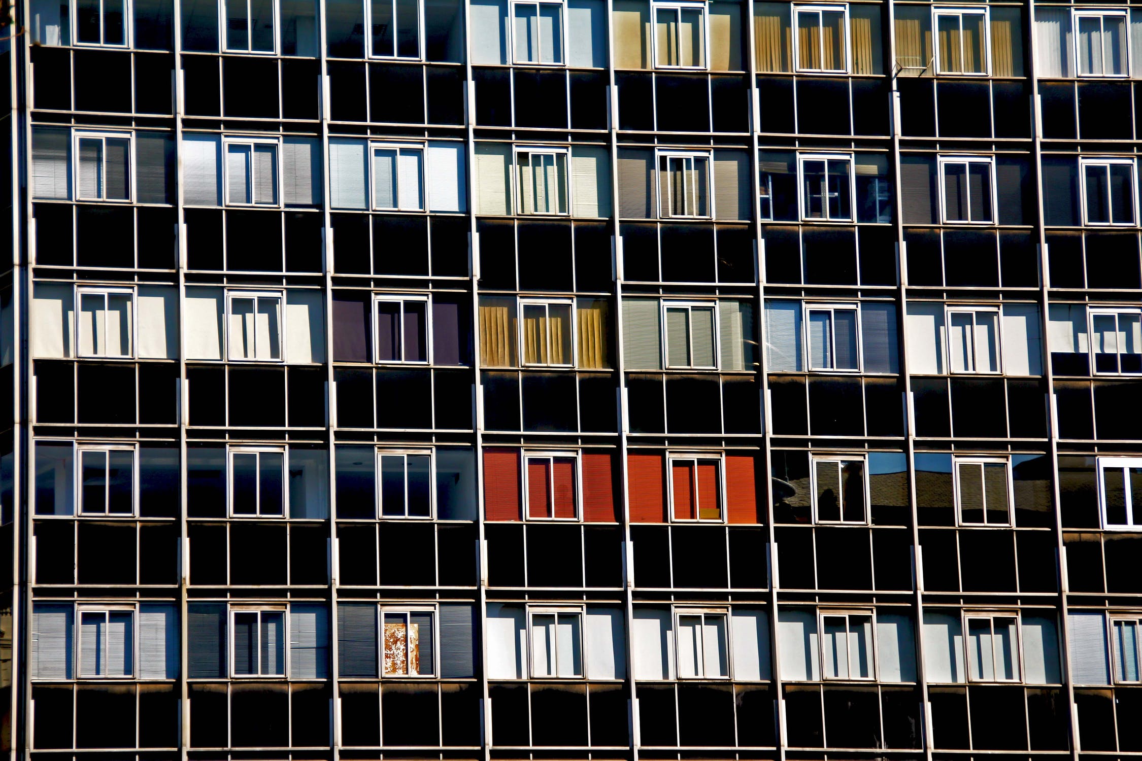 Facade of a modern apartment building with a pattern of colorful balconies and tenants waiting.