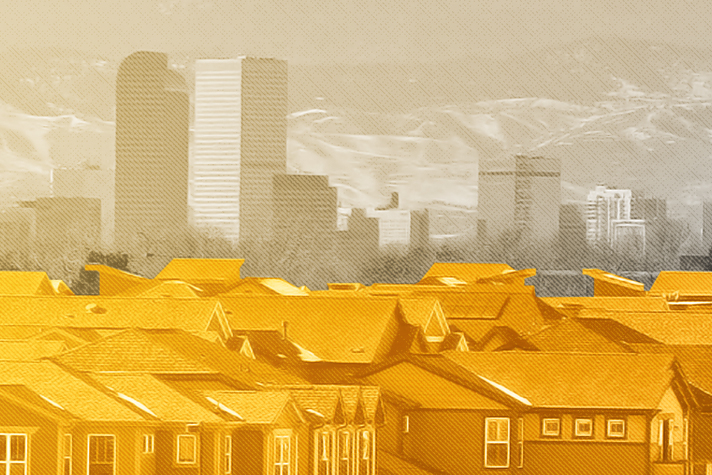 Urban skyline with residential rooftops in the foreground, under a hazy orange sky.